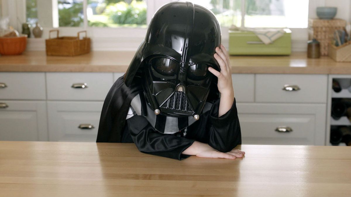 Ein Junge in einem Darth Vader-Kostüm sitzt mit dem Kopf in der Hand