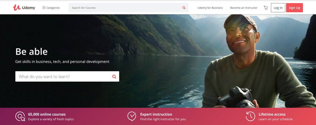 Online-Codierungskurse: Udemy-Homepage mit lächelndem Mann mit einem Hintergrund im Flusstal